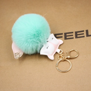 Detail of mint green faux fur fox pompom keychain with gold glitter ears and lobster clasp