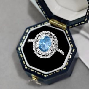 Close-up of S925 silver ring with blue oval zircon in a blue velvet jewelry box
