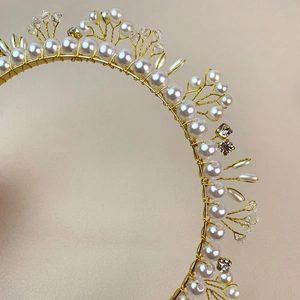 Elegant handmade pearl and crystal headband crown on a soft pink background