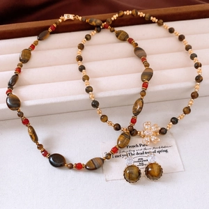 Détail de parure de bijoux en œil de tigre plaqué or 18 carats avec nœuds en zircon