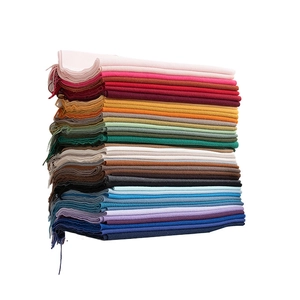 Stack of colorful cashmere-feel scarves with fringe tassels in various vibrant solid tones