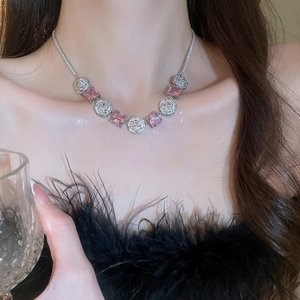 Macro shot of silver necklace with pink square gemstones and pavé zircon flower charms