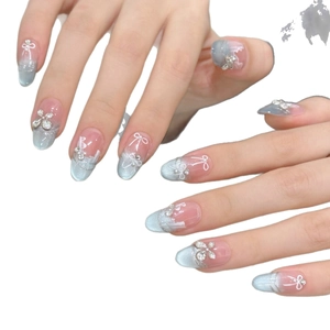 Faux ongles œil de chat bleus avec nœud 3D et strass sur fond blanc minimaliste