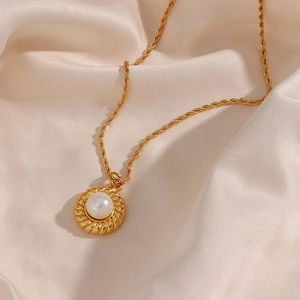 Gros plan d'un collier vintage plaqué or 18K avec pendentif perle sur tissu en soie