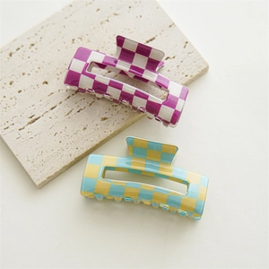 Detail of checkered pattern hair claws in purple and yellow on marble stone