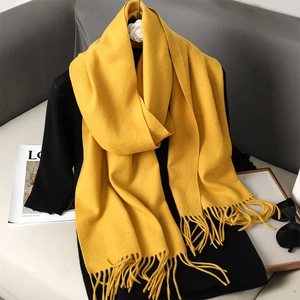 Detail of yellow cashmere-feel scarf featuring stylish fringe edges and soft texture