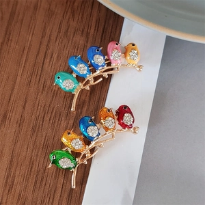 Detailed macro view of two bird brooches with colorful enamel and rhinestone accents