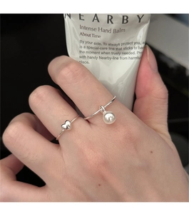 Close-up of 925 sterling silver heart ring and white pearl pendant ring set on finger