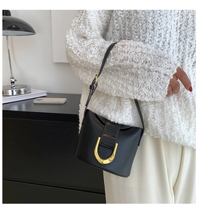 Detail of a black leather handbag with a prominent U-shaped gold metallic buckle