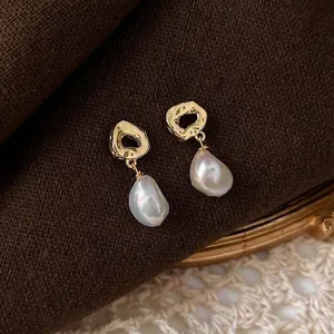 Baroque irregular freshwater pearl earrings with hammered gold metal base on fabric