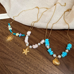 Detailed close-up of gold starfish and shell pendant necklaces with pearls and colorful stones