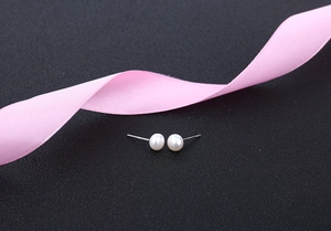 Close-up of elegant S925 silver stud earrings with white freshwater pearls on grey surface