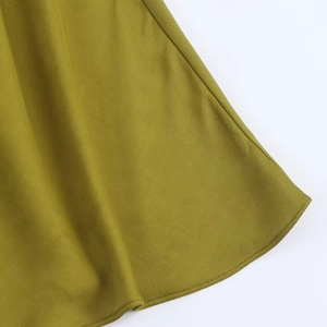 Detailed close-up of grass green satin dress hem showing high-quality stitching and fabric