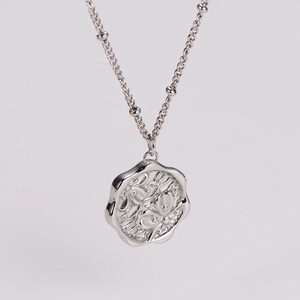 Detail shot of silver cherry blossom pendant with floral relief and wavy edges on beaded chain