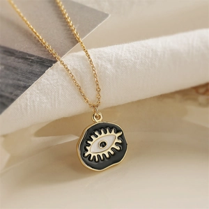 Gold evil eye pendant necklace with black enamel inlay and eyelash details on chain