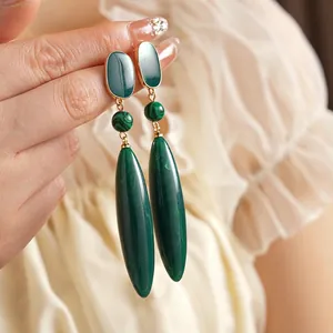 Retro emerald green malachite drop earrings with elegant gold metal accents on model
