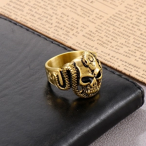 Macro view of vintage gold skull and snake ring on black leather with a retro paper backdrop
