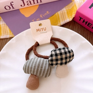 Close-up of two plaid mushroom hair ties made of soft cotton on a white ceramic plate