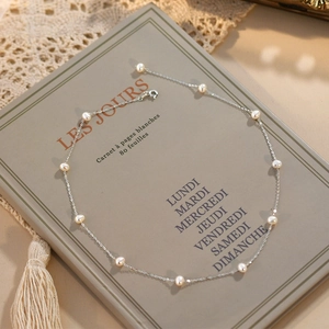 Detail of freshwater pearl necklace on vintage notebook with elegant lace accents