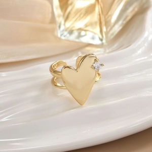 Close-up of a gold heart open ring with a small diamond inlay on a ceramic tray