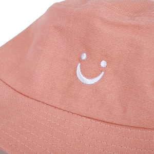 Close-up of a pink cotton canvas bucket hat showing white embroidered smiley face and stitching