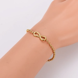 Golden infinity symbol beaded bracelet for women shown on a model hand at a 45-degree angle