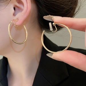 Close-up of large gold-tone hoop clip-on earrings with clear silicone comfort pads