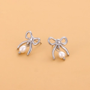 Détail de boucles d'oreilles nœud avec perles gouttes blanches sur fond beige