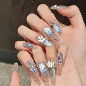 Detailed macro view of coffin-shaped cat-eye press-on nails with blue floral art and pearls