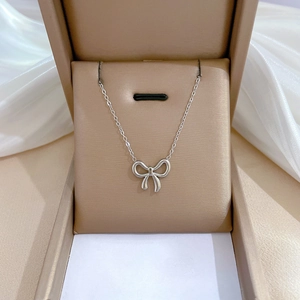 Detailed view of silver titanium steel bow necklace elegantly placed in a beige gift box