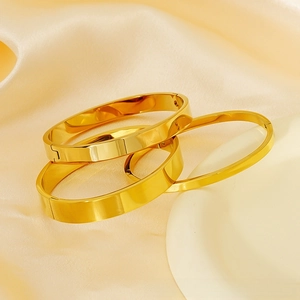 Detailed view of stacked 18K gold-plated minimalist hinged bangles on silk fabric