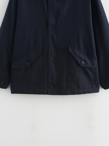 Detailed view of navy blue cotton jacket featuring large flap pockets and resin buttons