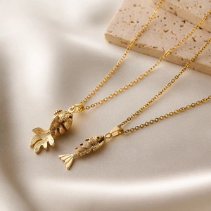 Elegant champagne gold koi and goldfish pendant necklaces on marble background