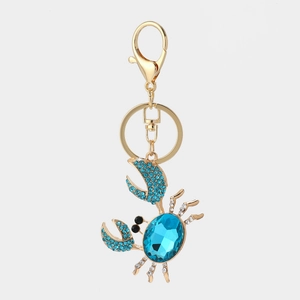 Close-up of a golden crab keychain featuring vibrant blue rhinestones and detailed craft