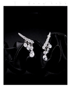 Macro shot of silver drop earrings with shimmering pavé diamonds and pear-cut zircon stones