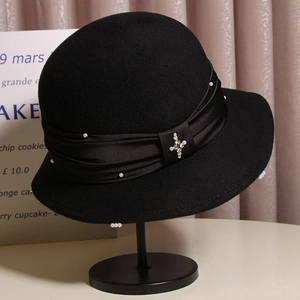 Close-up of black wool fedora featuring delicate pearls and a sparkling star brooch detail