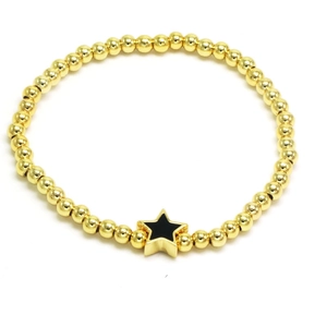 Detail of gold beaded bracelet featuring a black star charm on a clean white background