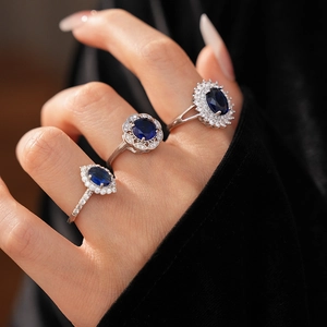 Detailed close-up of three silver flower rings with navy blue zircons on a hand