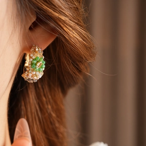 Close-up of vintage style round hoop earrings with green and pearl glass beads on model