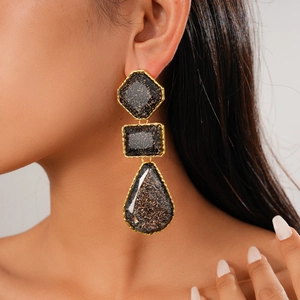 Détails des boucles d'oreilles géométriques en résine dorée sur mannequin