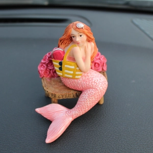Cute mermaid car dashboard ornament with red hair and pink tail on a wooden stool