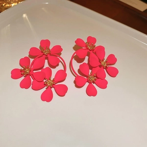 Detail showing matte rose red flower earrings with golden stamen on a white tray