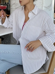 Macro detail of the lightweight black striped loose blouse in a casual dining setting