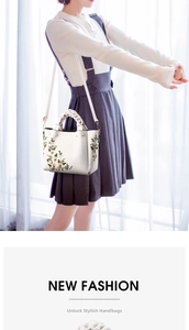 Exquisite floral embroidery detail on white handbag with woven handles and strap