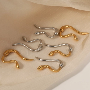 316 stainless steel snake shaped stud earrings in gold and silver on beige fabric