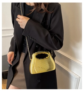 Detail of elegant gold metal cage handbag with fine chain strap on a black suit blazer