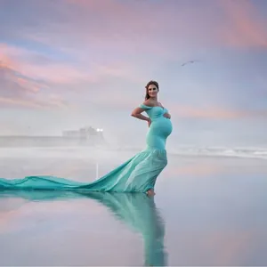 Elegant off-shoulder maternity photoshoot gown with long chiffon tail on the beach