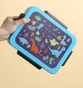 Close-up of blue bento box featuring a cartoon dinosaur world print on the lid