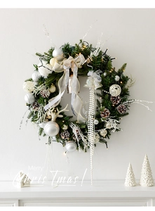 Détail d'une couronne de Noël argentée et blanche avec pommes de pin et lumières LED