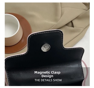 Détail du fermoir magnétique en métal d'un sac à bandoulière en cuir noir et rose